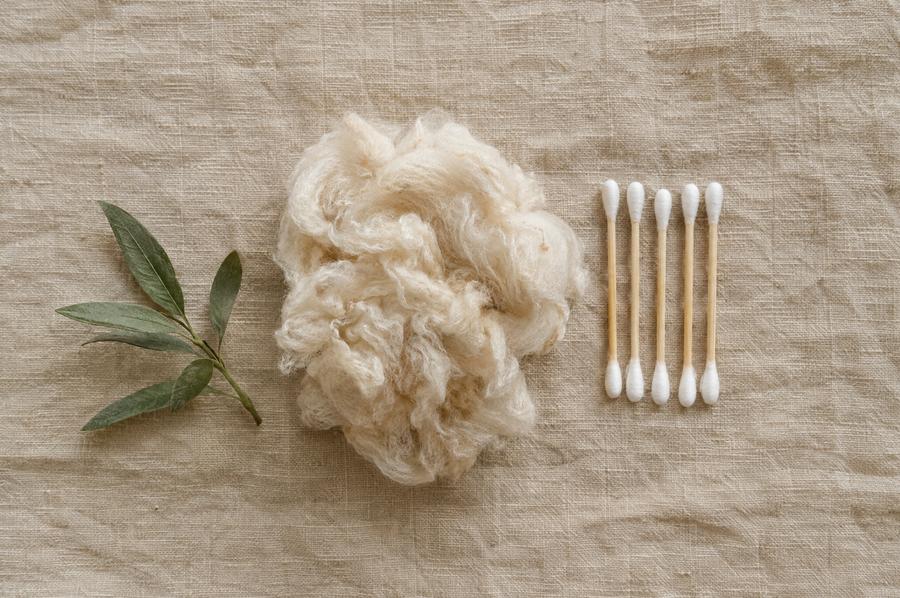 Raw unbleached cotton fibers and bamboo cotton swabs on natural linen